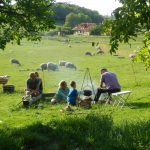 Grasveld op een kampeerveld in Slowakije met schapen en een vuurtje met een kookpot erboven
