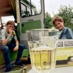 Twee jongens met een glas drinken voor een van de campers van Tralaluna in Nederland