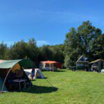 Een kampeerveld met verschillende kampeermiddelen op Natuurkampeerterrein de Voscheheugte