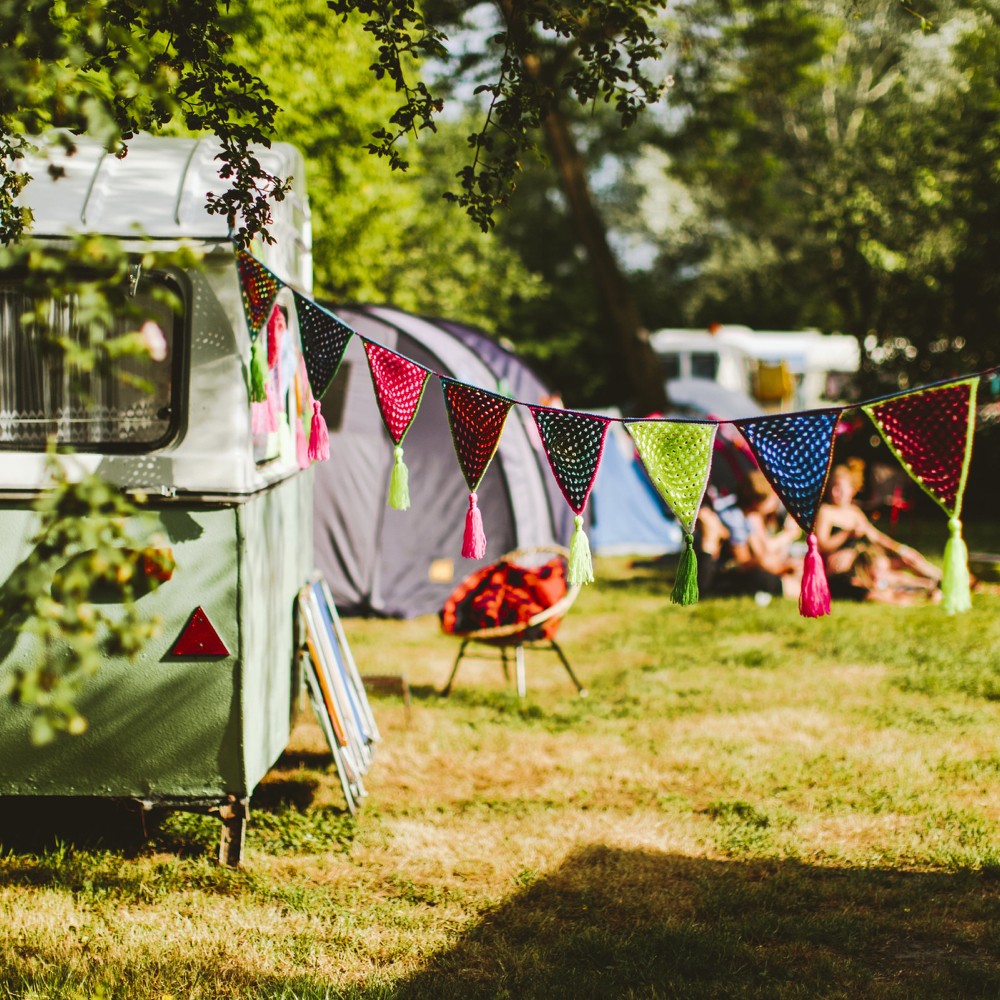 Een mintgroene caravan met een vlaggetjes lijn op Camping BuitenLand