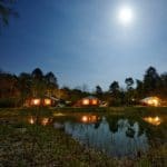 Drie safaritenten in de nacht aan een meer op Landgoed Börkerheide