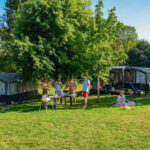 Een kampeerveld op Camping Vallée de Lignac met twee tenten en twee gezinnen die samen aan het koken zijn