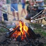 Een kampvuur met kinderen die marshmallows boven het vuur houden