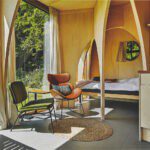 Twee stoelen en het bed van een cabin in het bos van Noord-Holland