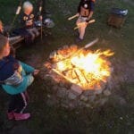 Kampvuur met kinderen eromheen die marshmallows aan het bakken zijn