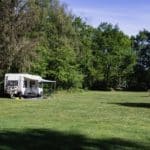 Caravan met luifel op een groen kampeerveld op een natuurcamping in het zuiden van Nederland