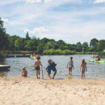 Strand met een meer en kinderen op een natuurkampeerterrein in Noord-Brabant
