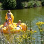 Geel opblaas speelgoed in het water met spelende kinderen