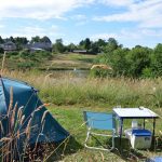 Camping 3Etangs ligt aan drie meren. Een blauwe tent met tafel en blauw stoeltje in het gras