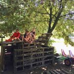 Een stapel palets met daarop jongeren onder een boom op een kindvriendelijke camping in Brabant