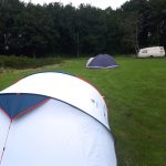 Kampeerveld met twee tenten en in de verte een caravan