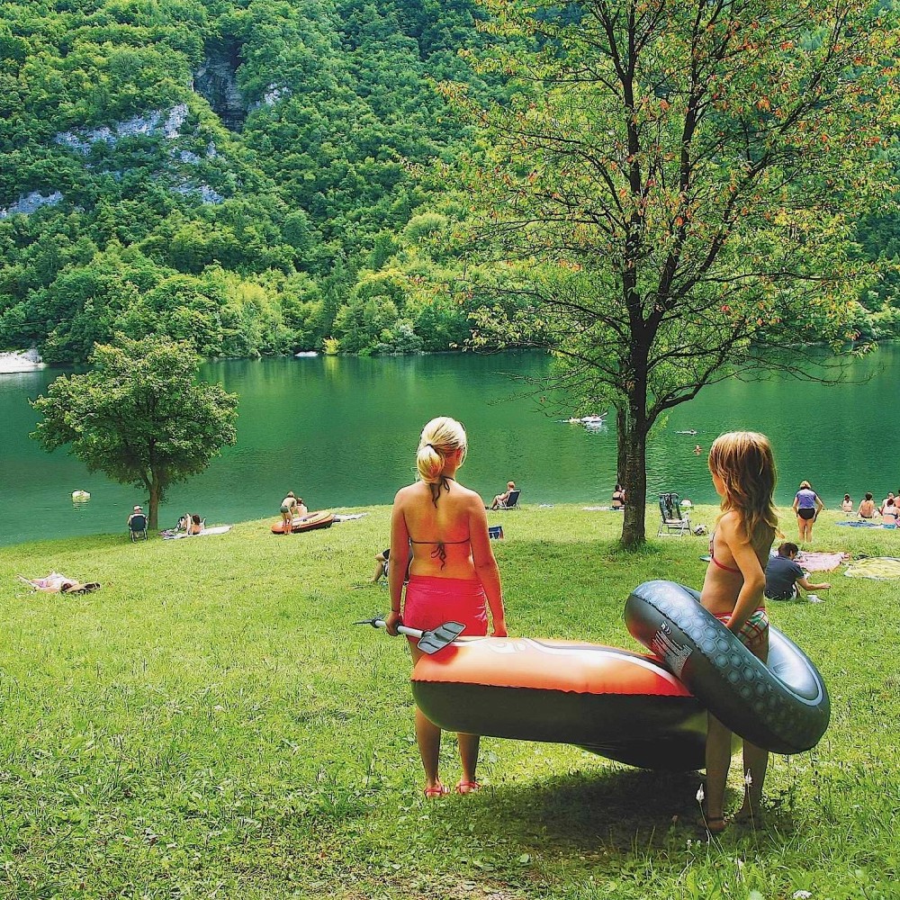 Twee meisjes met zwembanden en een rubberboot aan de waterkant op het gras