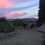 Een groep kinderen op de camping, naast een tent in de avondschemering