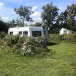 Een kampeerplek met caravan en privé sanitair op camping Strand49