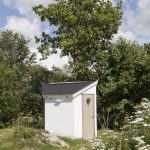 Een wit (privé) sanitair huisje dat hoort bij een kampeerplek.