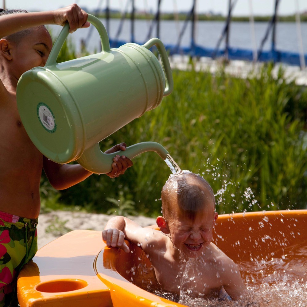 Jongetje in een oranje dutch tub krijgt een gieter water over zich heen