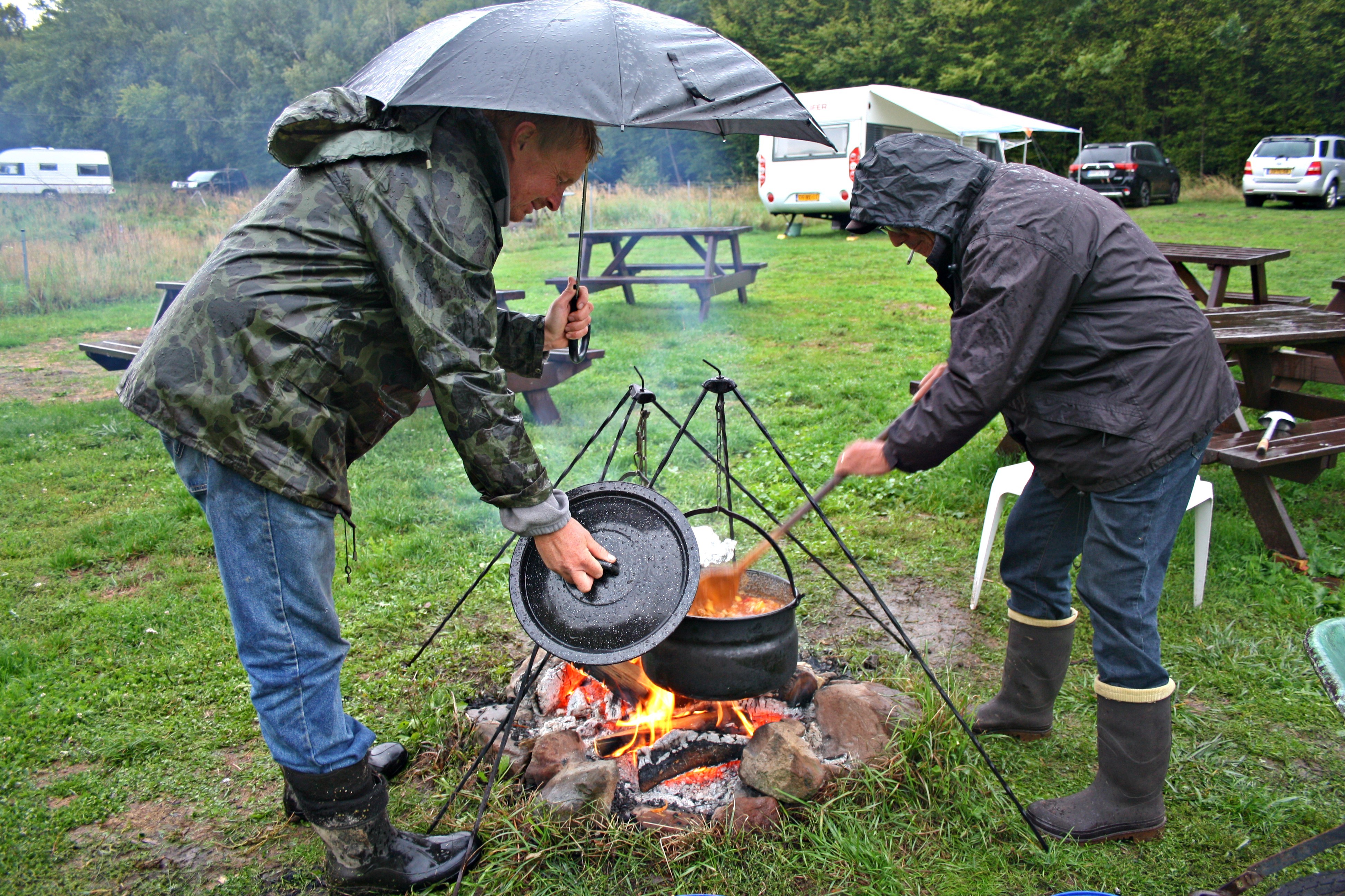 In de regen, boven een vuurtje wordt goulash gekookt in een Dutch Oven.