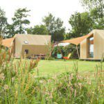 Twee design Ecolodges van hout op het kampeerveld.