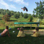 Een jongen op een trampoline met drie kinderen die toekijken op kindvriendelijke camping Villa Bussola