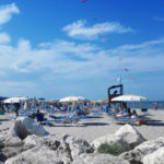 Stenen met strand erachter en strandbedjes aan de Adriatische zee