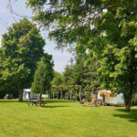 Groen grasveld met een caravan en een vouwtent op een camping dichtbij de Duitse grens
