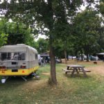 Caravan met boom en picknicktafel op een natuurcamping in Groesbeek
