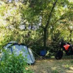 Tent op een kampeerplek omringd door bomen op een natuurcamping in Frankrijk