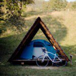 Tent overdekt met een houten structuur met een fiets ervoor op een kampeerveld in de Sloveense regio Savinjska
