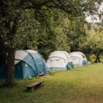 Drie tenten op een groen kampeerveld in de Sloveense regio Savinjska