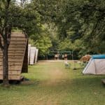Kampeerveld met huuraccommodaties een tent en een volleybalveld op Camping Naturplac