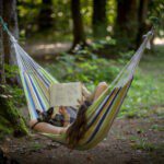 Vrouw die een boek aan het lezen is met haar hond in een hangmat in het bos in Slovenië