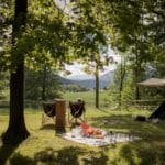 Picknickkleed met twee stoelen ervoor op een groene kampeerplek op Forest Camping Mozirje
