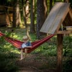 Jongetje in het bos in een hangmat aan het lezen