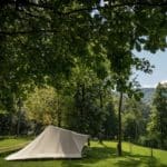 Beige tent op een groen kampeerveld omringd door bomen op Forest Camping Mozirje