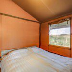 Slaapkamer met bed en raam in een safaritent