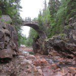 Rotsen in een rivier met een stenen brug erover in het zuiden van Zweden