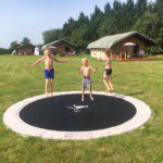 Drie kinderen op een trampoline met drie safaritenten erachter op Domaine Saint Esselin in Zuid-Frankrijk