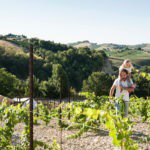 Man met dochter op de schouder op een wijngaard in Italië