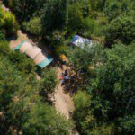 Bovenaanzicht van een kampeerplek met een beige tent erop omringd door bomen op camping La Cazette