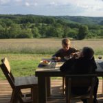 Twee kinderen aan het eten op de veranda van een safaritent met uitzicht op het Franse platteland