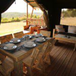 Houten tafel gedekt vier houten stoelen eraan in een safaritent in Frankrijk