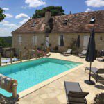 Zwembad met ligbedjes ernaast en een oud gebouw in Zuid-West Frankrijk