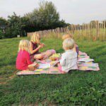 Vier kinderen op een picknickkleed in een weiland
