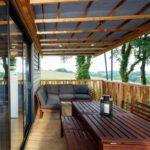 Veranda met houten meubels in een lodge met uitzicht op groene heuvels in Frankrijk