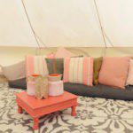 Zithoek met kussens en een roze tafel in een bell tent