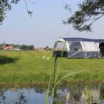 Blauwwitte tent op een kampeerveld naast een sloot in Brabant