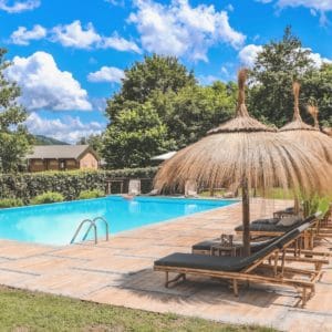 Zwembad met ligbedjes en parasollen op glamping Rancone Lodges