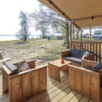 Drie stoelen op de veranda van een safaritent met uitzicht op een meer in Flevoland