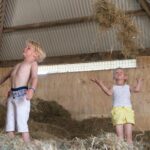 Twee kinderen in een hooiberg op een boerderij in Zuid-Holland