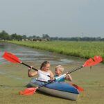Twee kinderen aan het kanoën op een kanaal in Zuid-Holland